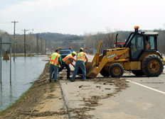 Highway workers, front loader clearing debris from road
