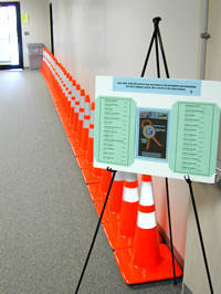 A line of 28 orange cones against a wall