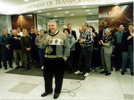 Man at microphone talking to group of employees