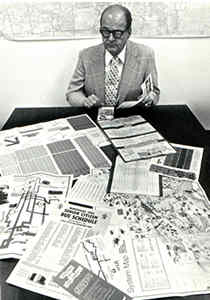 Man sitting behind table of maps (b&w)