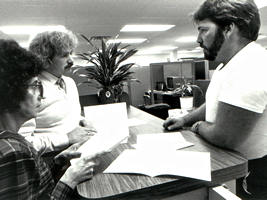 1 woman, 2 men talking over counter