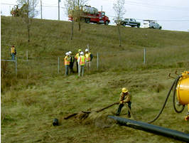 People in field laying fiber-optic cable