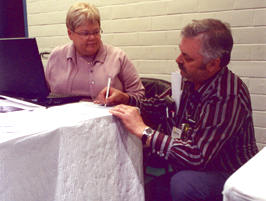 Man signing paper for woman