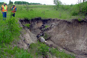2 workers looking at hole caused by flood