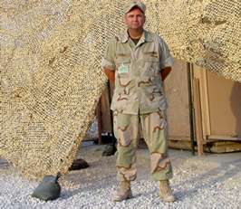 Man standing in fatigues in desert location
