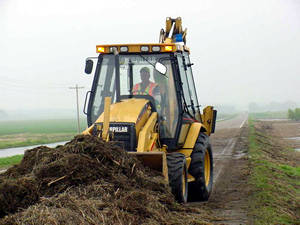 Man in a backhoe pushing debris