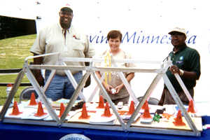 2 men, woman behind model bridge