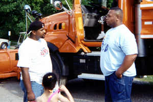 2 men, girl next to orange truck