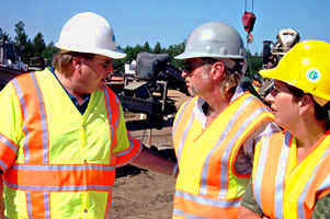 3 people in safety vests, hard hats