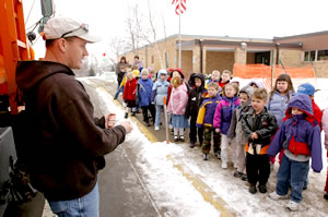 School kids looking at man next to orange truck