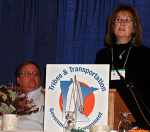 Man watches woman at lectern speak