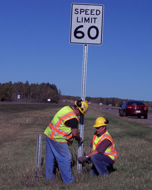 2 men putting up speed sign