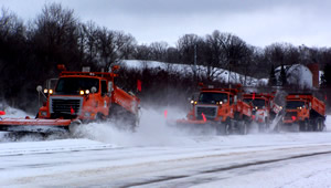 4 snowplows plowing