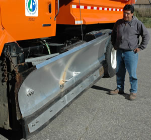 Man standing next to plow blade