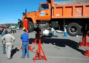 3 men looking at elevated orange truck