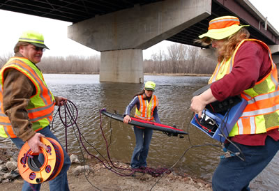 3 people measuring under bridge