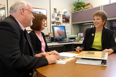 Man, 2 women seated at desk