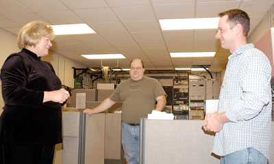 Woman, 2 men standing in office area