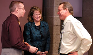 Woman, 2 men standing in office area