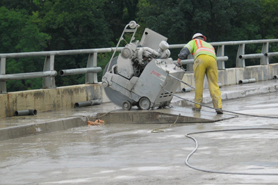 Crew member sawing the sidewalk and bridge railing into sections. Photo by Jenny Seelen