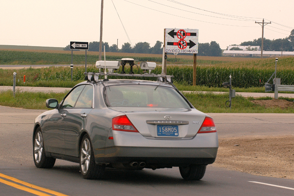 A test car crammed with electronic sensors and computers approaches the warning signal at the intersection of Hwy 52 and Goodhue County Road 9 near Cannon Falls. Photo by David Gonzalez