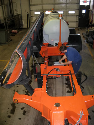 Man works on tow plow blade