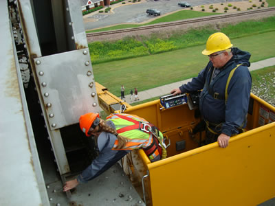 2 people in bucket inspect bridge