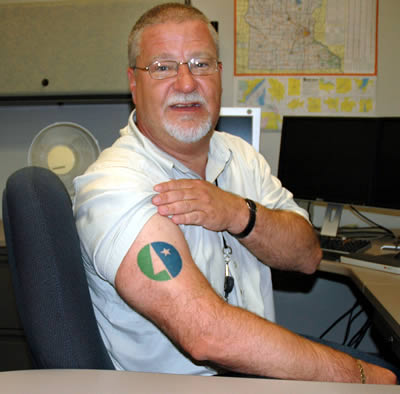 Ken Gilman flexes his Mn DOT muscle and flashes his new tattoo