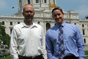 Erik Rundeen and Marc Briese pose for a photo in front of the MN Capitol