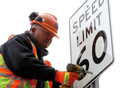 Photo of Dennis Salzwedel changing speed limit sign