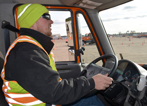 Photo of Adam Hovden in the drivers seat of a snowplow.