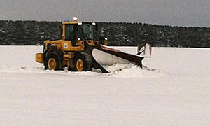 Photo of MnDOT plow moving snow in a farmers field.