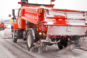 Photo of a snowplow distributing salt on a highway.