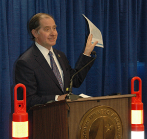 Commissioner Charlie Zelle waving funding chart at news conference