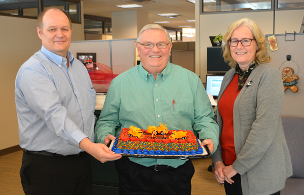 2 men and woman holding cake