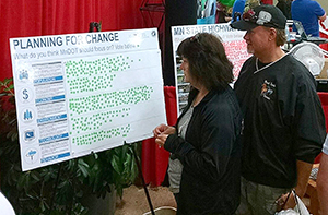 Photo of Tina Smith talking to a visitor at the MnDOT State Fair booth. 