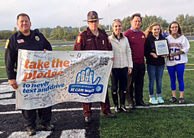 Photo of Holly Kostrzewski and law enforcement officers presenting award to Esko High School.