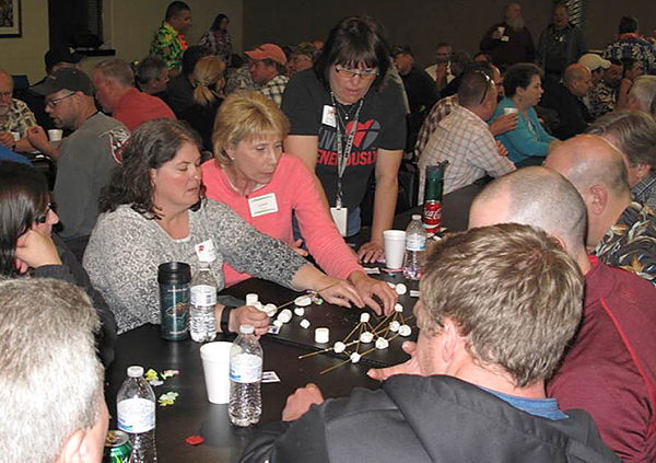 Photo of District 3 employees working with noodles and marshmellows to create a bridge.