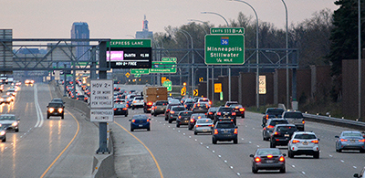 Traffic on I-35E heads south towards downtown St Paul. MnPASS toll signs are lit overhead.