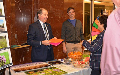 Two men interact with visitors at information booth.