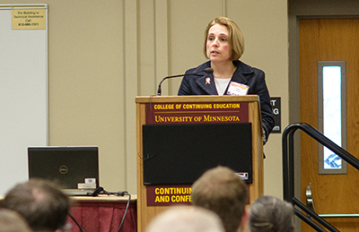 Woman standing at lectern addressing conference attendees