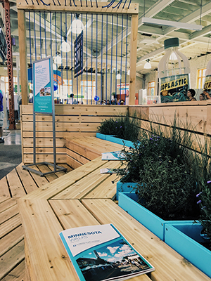 Wooden bench zig-zags in front of planters filled with low bushes, ornamental grasses