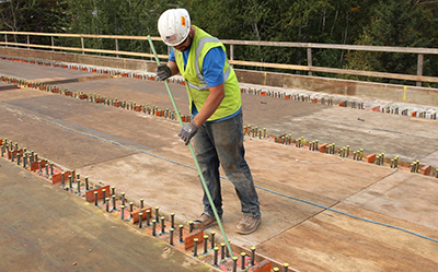 Construction worker on Beaver Bay Bridge breaks a ceramic insulator off a sheer stud