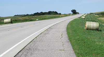 Photo of highway with hay bales in ditch.