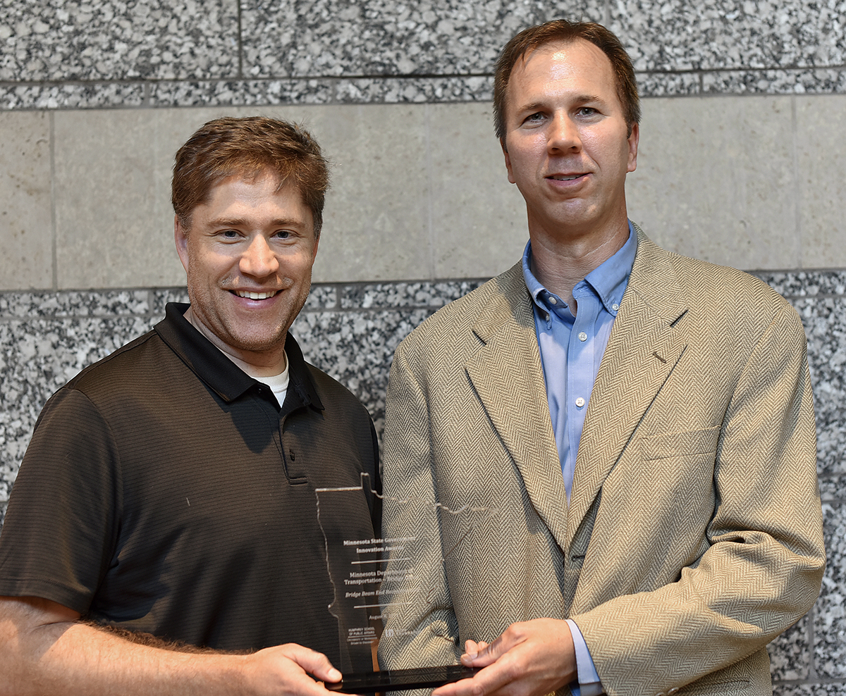 Two men pictured holding an award plaque