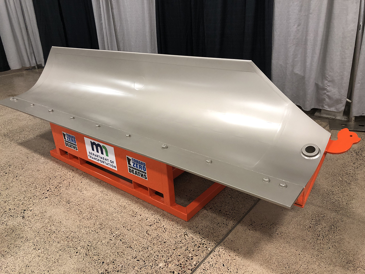 A very clean snowplow blade mounted on an orange metal stand.