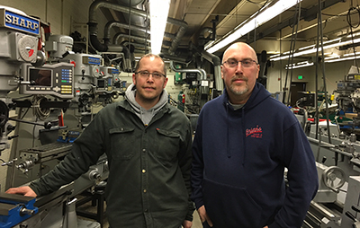 2 men standing in high school metal workshop