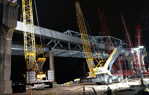 Yellow construction cranes lift tub girders during night installation at Red Wing Bridge.