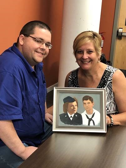 A son and his mother, posed near a painting of the man's grandparents.