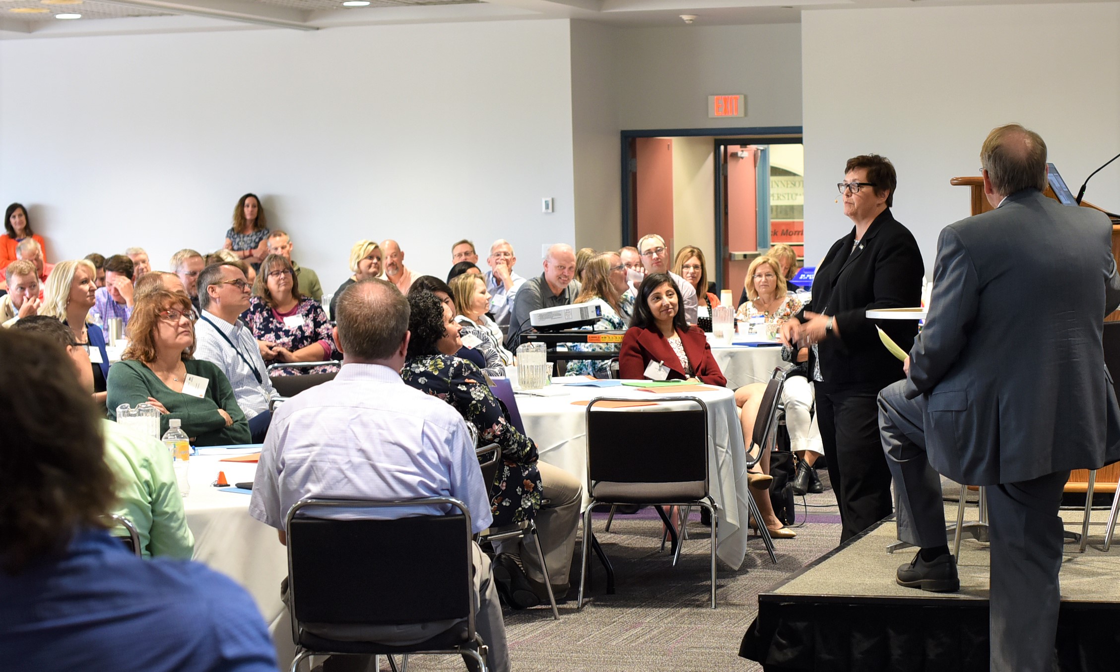 Commissioner Anderson Kelliher speaking before a large group. They are seated at tables and she is standing.